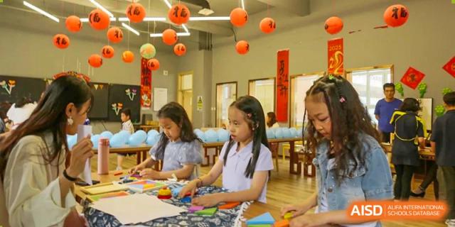 Female students engaged in an art or craft activity at desks, surrounded by festive paper lanterns and decorations, Brilliant Light School SJZ.
