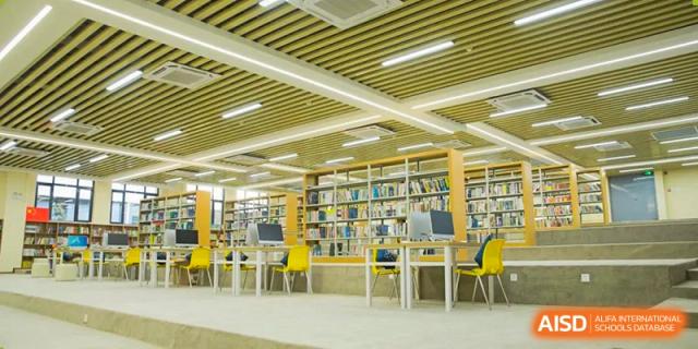 The school library interior showing rows of bookshelves and comfortable reading areas with yellow chairs, Brilliant Light School SJZ.