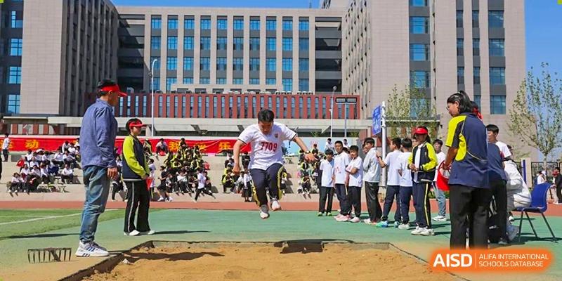 A male student competing in the long jump event during a school sports day at Brilliant Light School SJZ.