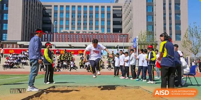 A male student competing in the long jump event during a school sports day at Brilliant Light School SJZ.