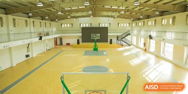 Interior view of a large, well-lit indoor basketball court and gymnasium at Brilliant Light School SJZ.