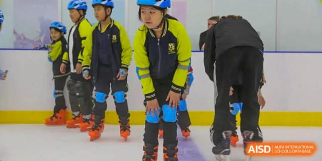 Students wearing bright yellow and blue jackets and helmets while roller skating indoors, Brilliant Light School SJZ.