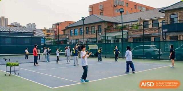 A student practicing jump rope on an outdoor tennis court with other students in the background, Brilliant Light School SJZ.