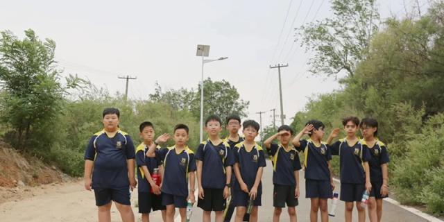 A group of male students in dark blue and yellow uniforms posing together on an outdoor sports field, Brilliant Light School SJZ.