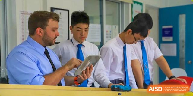 Two older male students in uniform collaborating and working on a tablet device in a classroom at Britannica International School, Shanghai.