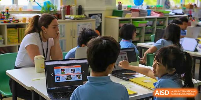 A student in uniform sitting at a desk and focused on a laptop screen during a lesson in a classroom at Britannica International School, Shanghai.