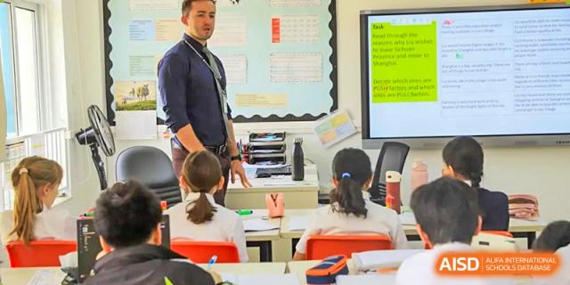 A female teacher instructing a group of young students seated at their desks in a classroom at Britannica International School, Shanghai.