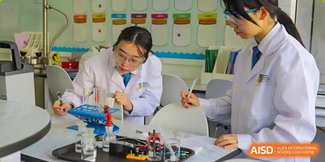 A female student in uniform working with beakers, test tubes, and other scientific equipment during a practical science lesson at Britannica International School, Shanghai.
