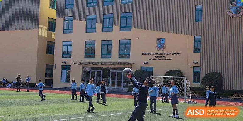 A group of students playing with a basketball-sized ball on the court in front of the main school building of Britannica International School, Shanghai.
