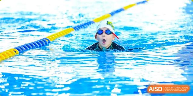 A student swimmer wearing goggles and a cap taking a breath during a swimming lesson in the school pool at Britannica International School, Shanghai.