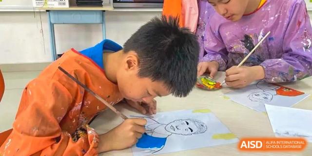 A close-up of a student in an orange shirt concentrating while drawing a portrait on paper in an art activity at Canadian International School of Hefei.
