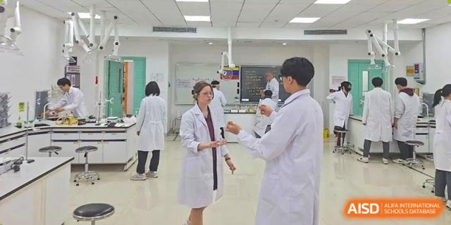 A female student in a lab coat talking with a male student in a lab setting, possibly a medical or dental lab, at Canadian International School of Hefei.