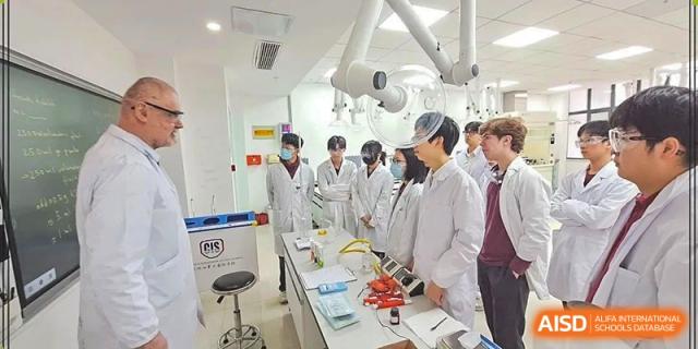 Students in white lab coats and surgical masks participating in a practical science or medical lab session at Canadian International School of Hefei.