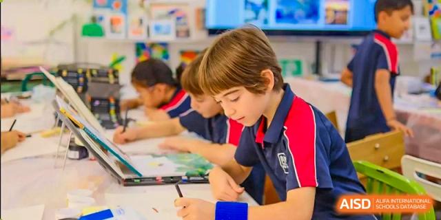 Two younger male students collaborating on a writing or drawing activity at a table in the school library at Canadian International School of Hefei.