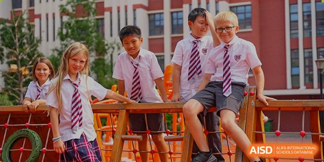 A group of older male students in school uniforms sitting and talking at an outdoor picnic-style table at Canadian International School of Hefei.