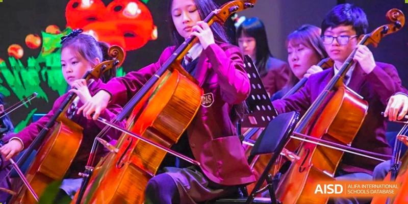 A student in a purple top playing the cello in an orchestra performance at Canadian International School of Hefei.
