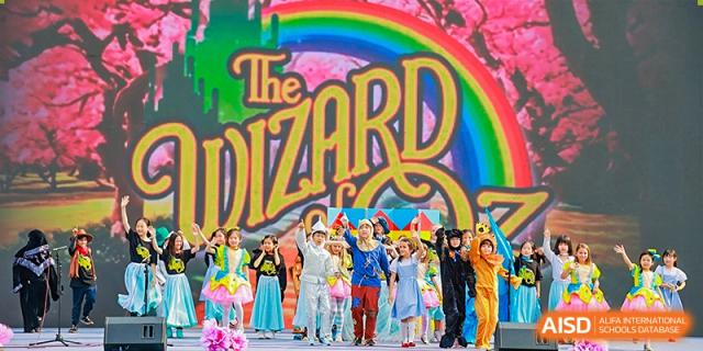 A large group of students in colorful costumes on stage at the finale of 'The Wizard' production at Canadian International School of Hefei.