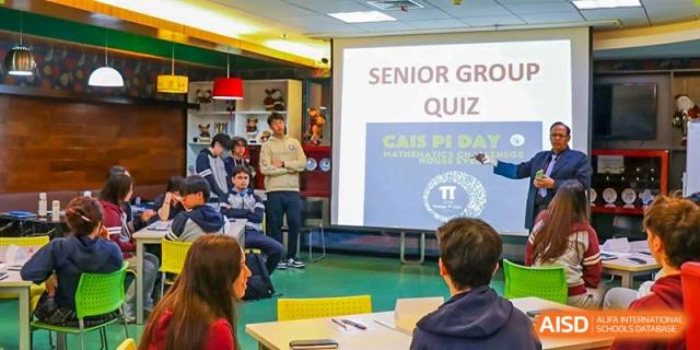 Students from Changchun American International School (CAIS) participating in a "SENIOR GROUP QUIZ" activity displayed on a large screen.