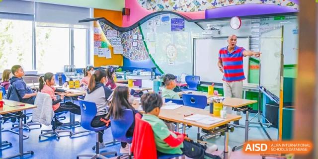 Students from Changchun American International School (CAIS) engaged in a collaborative project in a classroom decorated with maps and vibrant displays.
