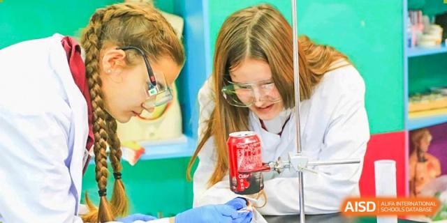 A female student from Changchun American International School (CAIS) wearing safety goggles and working with lab equipment in a science class.