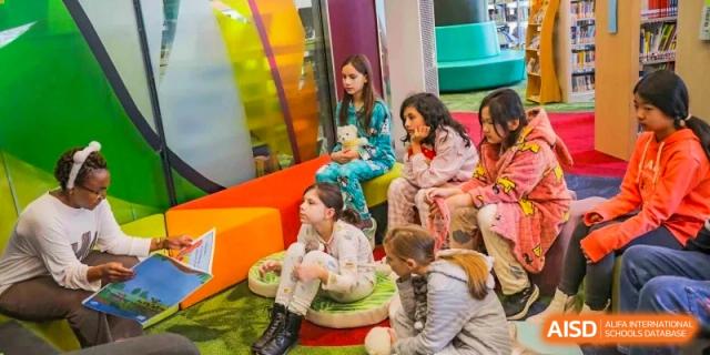 Young female students from Changchun American International School (CAIS) sitting together in a colorful, modern reading or play area.