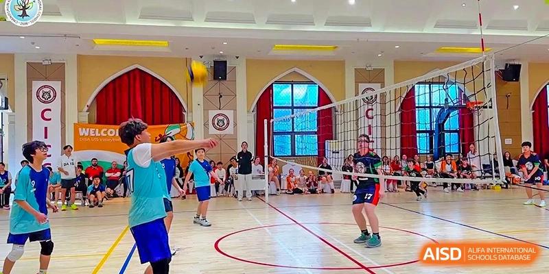 Students playing volleyball in a gymnasium with large windows at Changchun American International School (CAIS).