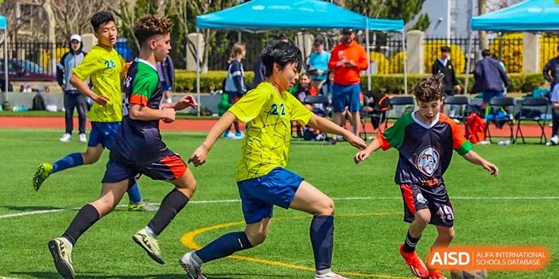 A student from Changchun American International School (CAIS) wearing a yellow jersey playing soccer outdoors.