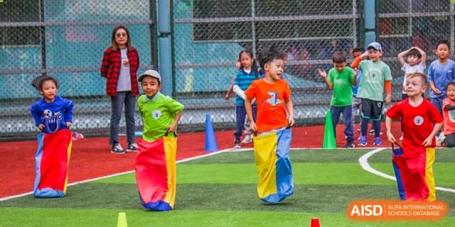 Young students from Changchun American International School (CAIS) participating in a sack race activity outdoors.