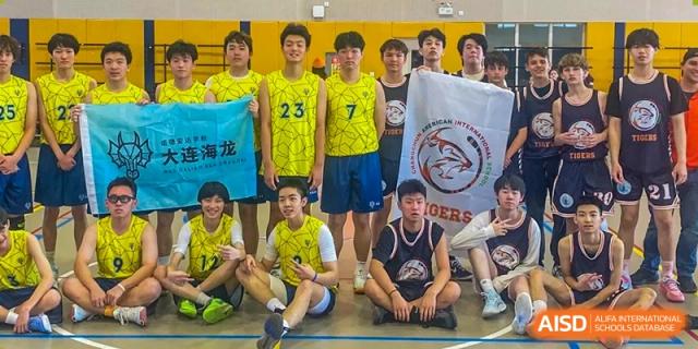 A team of students from Changchun American International School (CAIS) posing together with a banner after a sports game.
