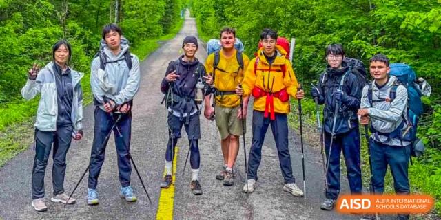 A group of students from Changchun American International School (CAIS) posing on a hiking or cycling trail during an outdoor expedition.