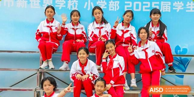 A close-up of a group of smiling female students in their red and white uniforms, sitting together for a photo, demonstrating camaraderie at Guiyang New World School.