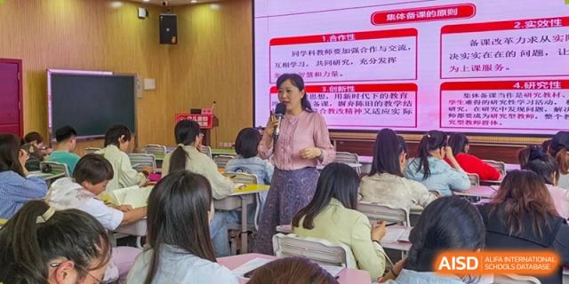 A teacher stands at the front of a class, actively lecturing students while presenting slides on a digital screen at Guiyang New World School.