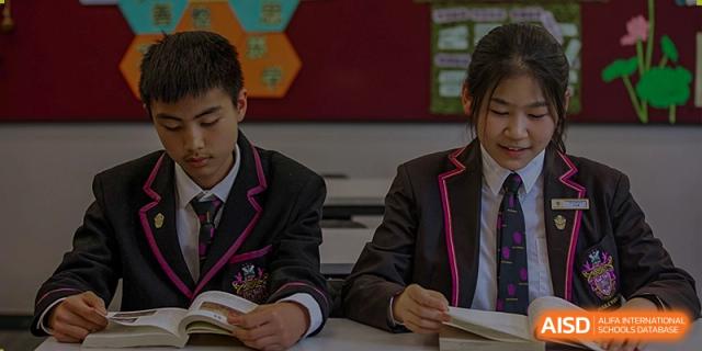 Two male students in uniform intently reading books at a desk in a classroom at Haileybury Schools, Tianjin.