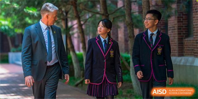 A female student in her school uniform standing outdoors on the campus of Haileybury Schools, Tianjin.