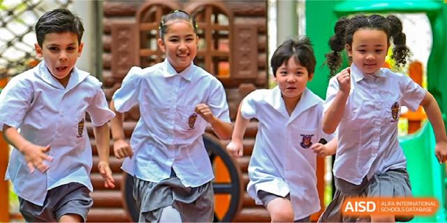 Two young female students smiling and running excitedly during an outdoor activity at Haileybury Schools, Tianjin.