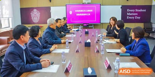 Adults, including staff and possibly school governors, seated around a large conference table during a meeting at Haileybury Schools, Tianjin.