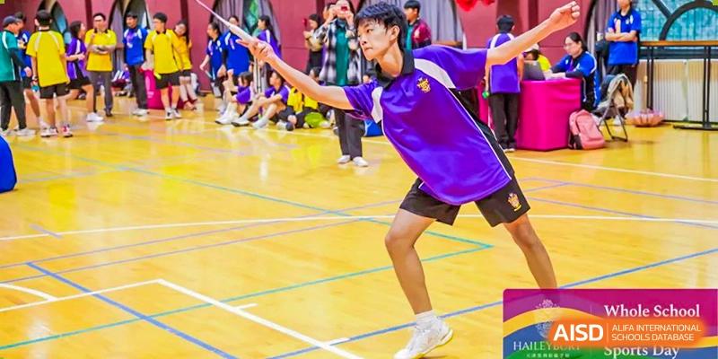 A student in a purple sports shirt playing badminton on an indoor court at Haileybury Schools, Tianjin.