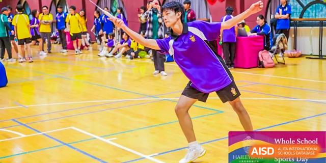 A student in a purple sports shirt playing badminton on an indoor court at Haileybury Schools, Tianjin.