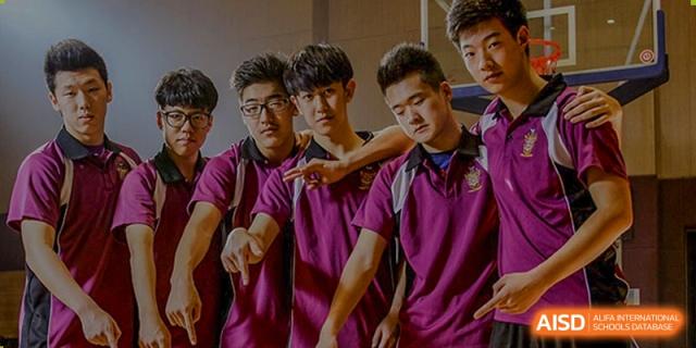 Four male students wearing maroon polo shirts posing seriously for a photo on the campus of Haileybury Schools, Tianjin.
