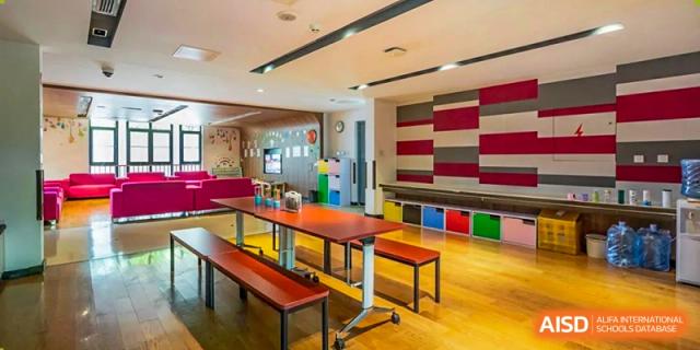 The bright, modern interior of the school dining hall or common area with long wooden tables and benches at Haileybury Schools, Tianjin.