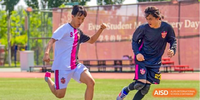 A student in a pink and white sports shirt running on the green sports field during an event at Haileybury Schools, Tianjin.