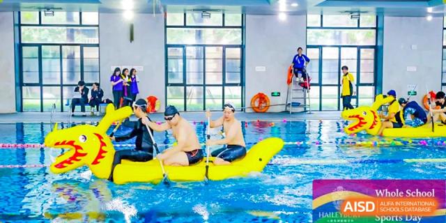 Students and staff participating in a fun raft or inflatable boat race in the school's indoor swimming pool at Haileybury Schools, Tianjin.