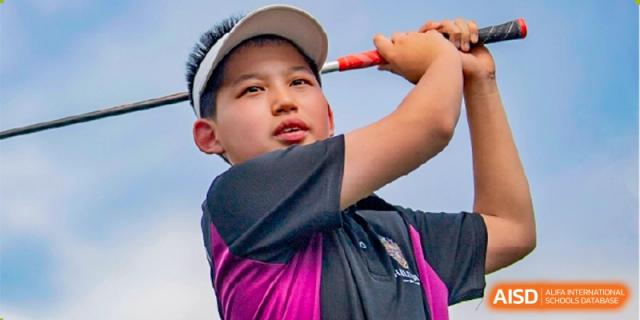 A close-up of a male student in a black and magenta shirt preparing to hit a ball or serve during a sports event at Haileybury Schools, Tianjin.