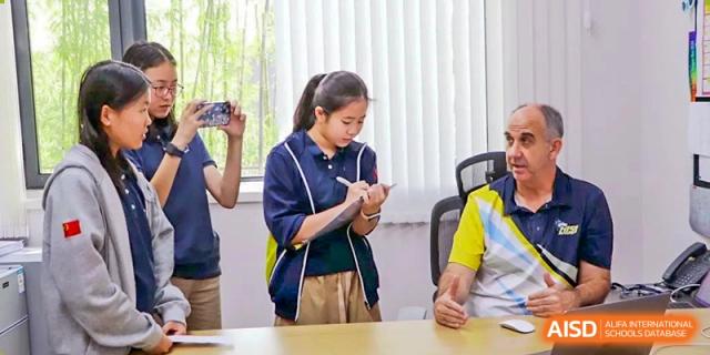 A female student from Hangzhou International School taking notes or participating in an activity at a desk.
