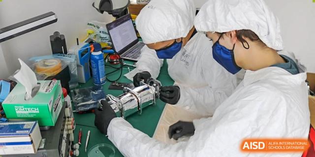 A student from Hangzhou International School wearing protective gear while working with robotics equipment.