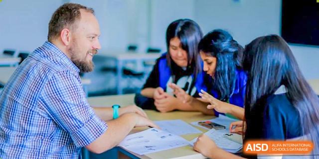 Hangzhou International School students collaborating on a project and reviewing papers at a table.