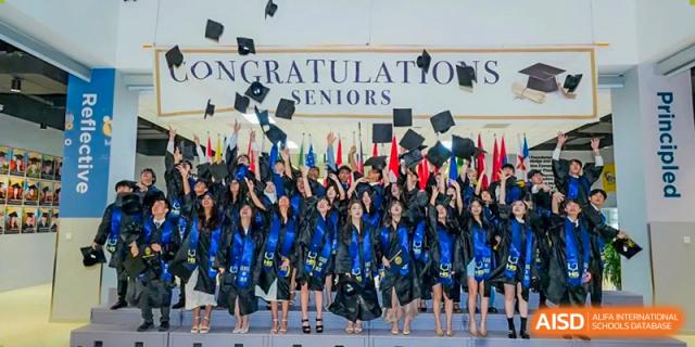 Recent graduates from Hangzhou International School tossing their caps in the air in celebration.