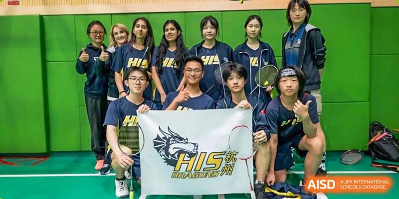 The Hangzhou International School Dragons sports team posing together with a banner after a game.