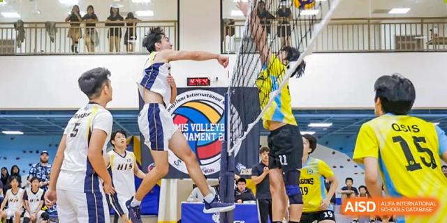 A volleyball player from Hangzhou International School spiking the ball over the net during a competition.