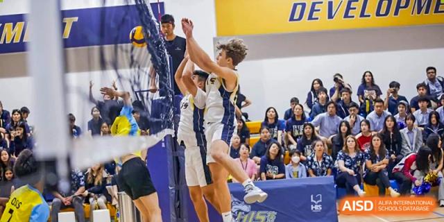 Two male basketball players from Hangzhou International School jumping to block a shot during a game.